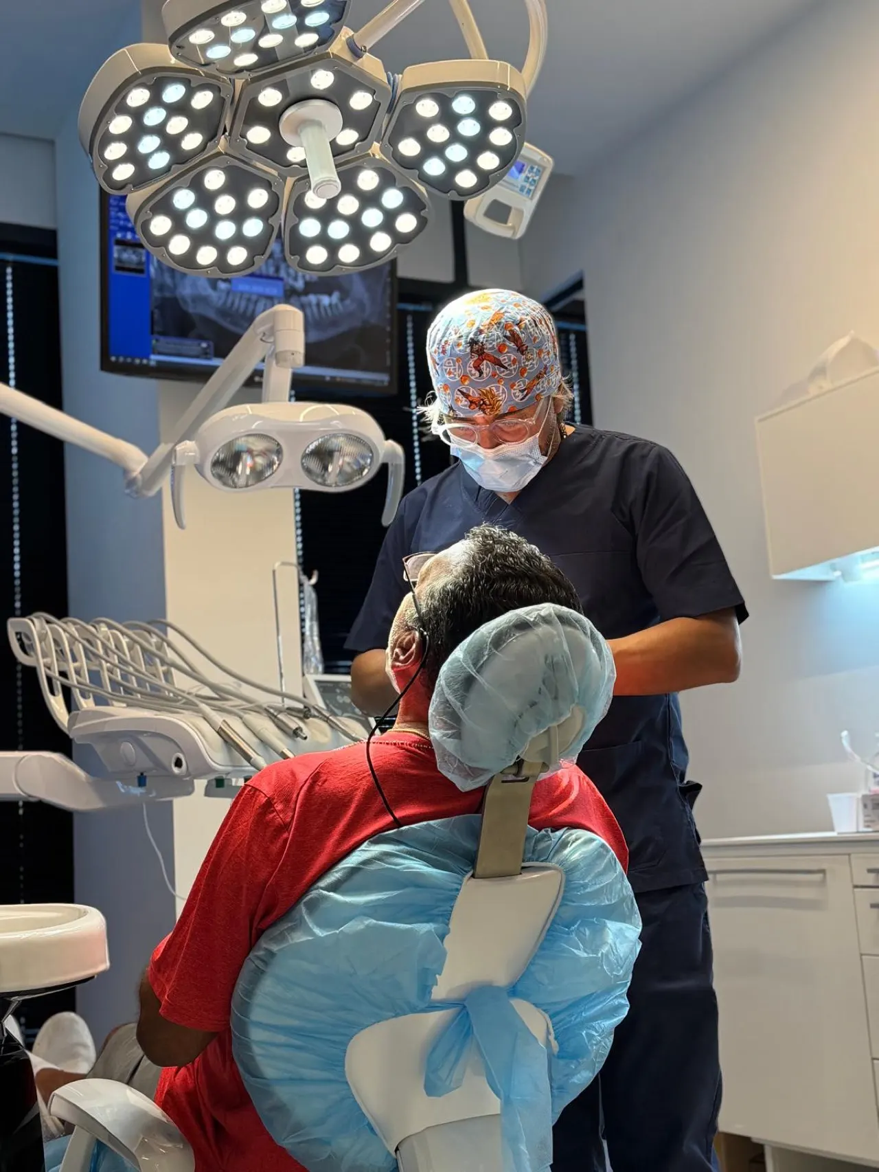 Un odontoiatra di Aurum Dentis al lavoro su un paziente sotto la lampada scialitica